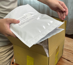 Person placing sealed pouch of bubble tea ingredients into a shipping box