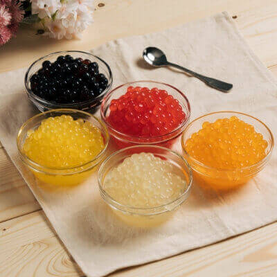 Colorful variety of Tapioca Boba including black tapioca and fruit popping boba in mango, lychee, strawberry, and passion fruit flavors
